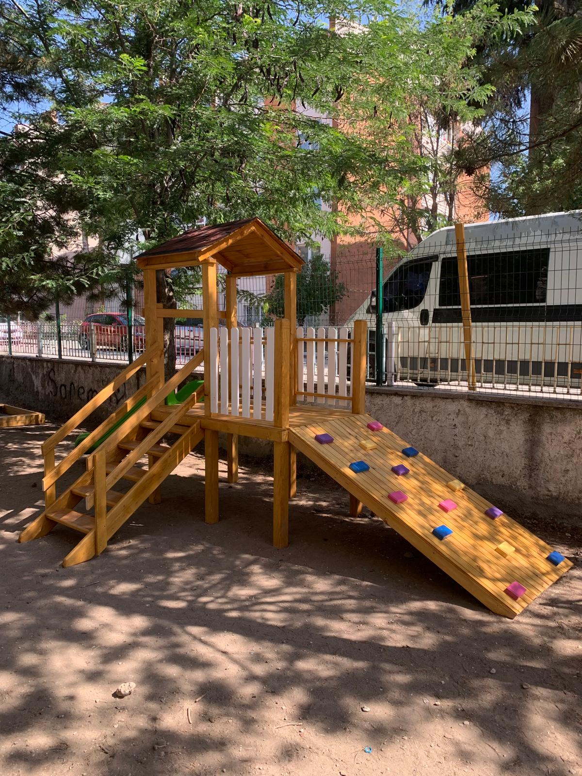 Ağaç gölgesinde Montessori ahşap oyun alanı